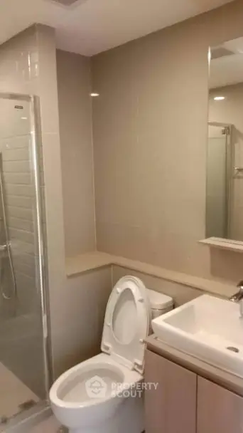 Modern bathroom with glass shower and sleek fixtures in contemporary apartment.