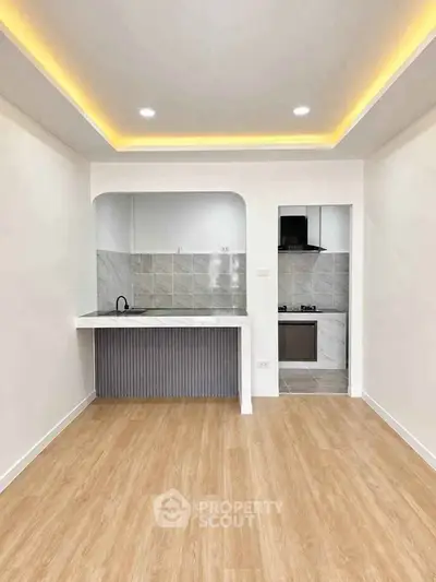 Modern kitchen with open layout and sleek design, featuring wood flooring and recessed lighting.