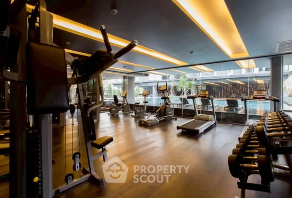 Luxurious gym with modern equipment and pool view in upscale residential building.