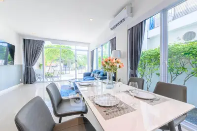 Spacious modern living room with dining area and large windows overlooking garden.