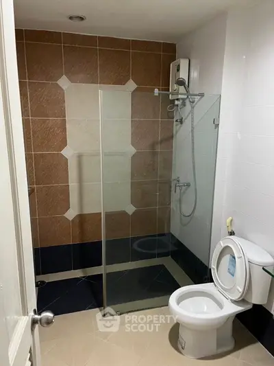Modern bathroom with glass shower and tiled walls in a real estate property.