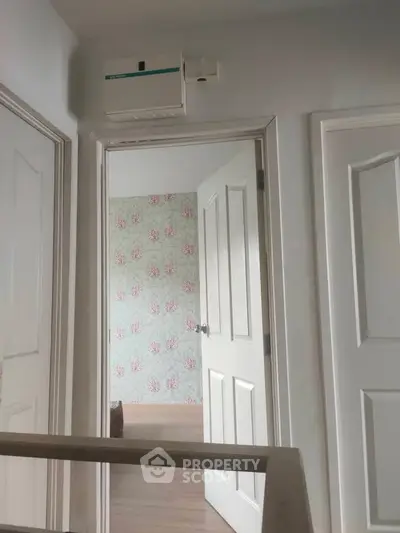 Charming interior hallway with floral wallpaper and white doors, showcasing a cozy and inviting home atmosphere.