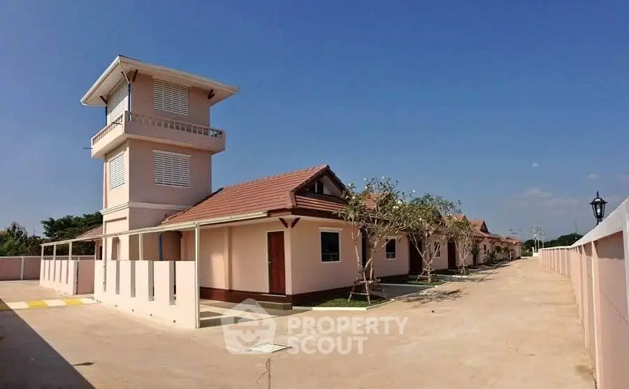 Charming residential complex with unique tower feature and spacious layout under clear blue skies.