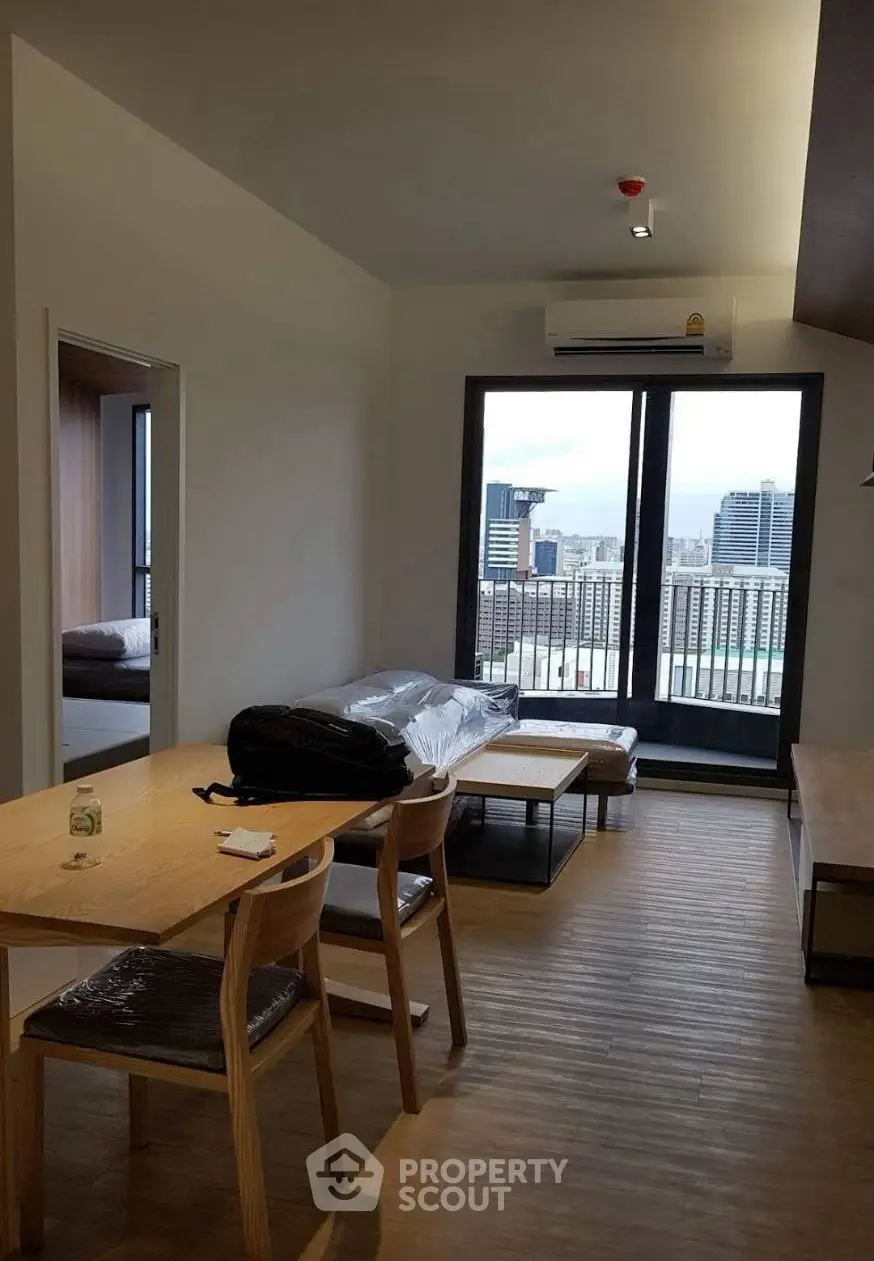 Modern living room with city view, featuring sleek furniture and large windows for natural light.