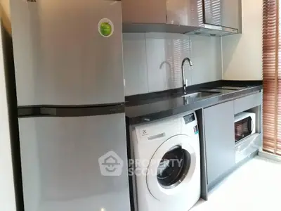 Modern kitchen with stainless steel fridge, washing machine, and sleek cabinetry.