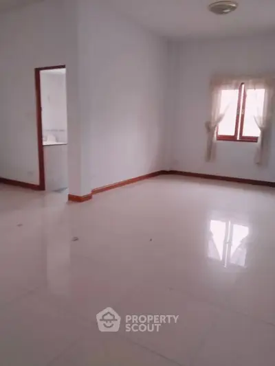 Spacious unfurnished room with tiled flooring and natural light from window.