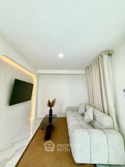 Modern living room with sleek design, featuring a plush sofa, wall-mounted TV, and elegant lighting.