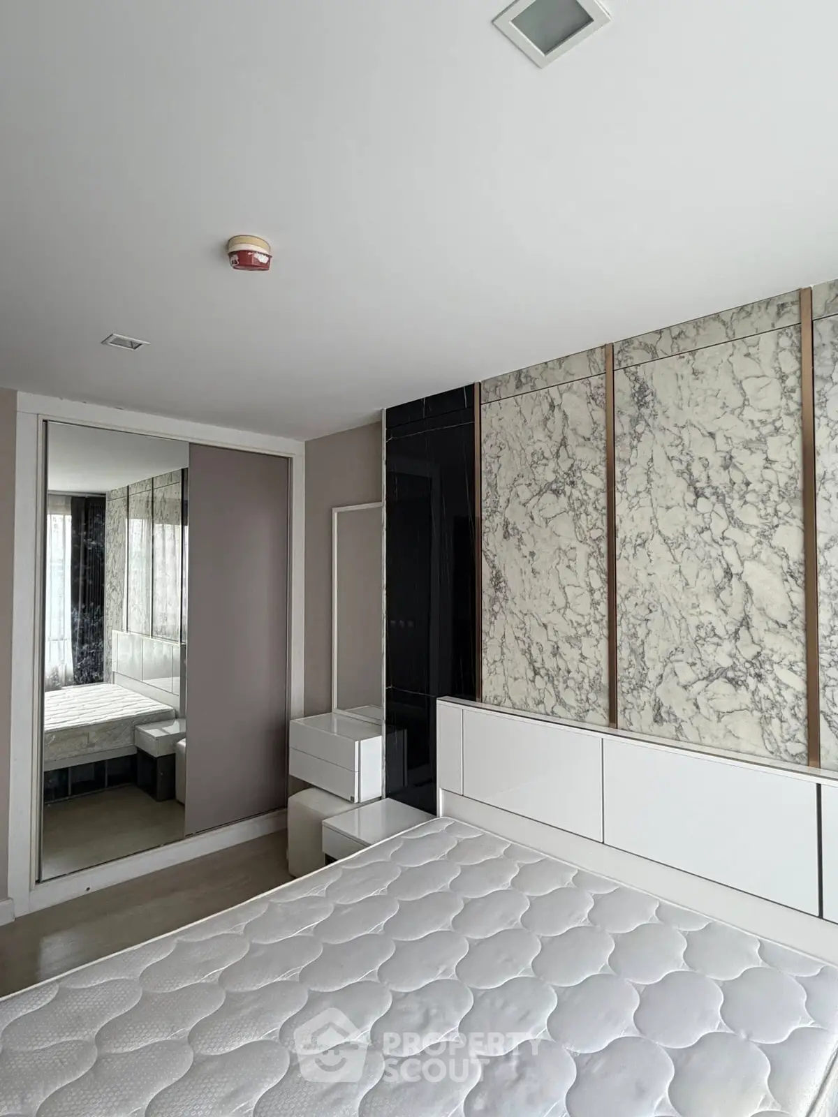 Modern bedroom with marble accent wall and large mirror closet