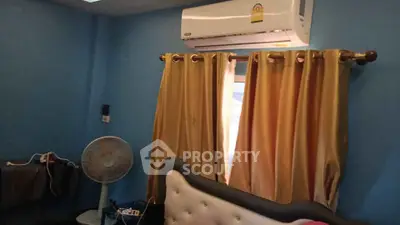 Cozy bedroom with blue walls, air conditioning, and elegant curtains.