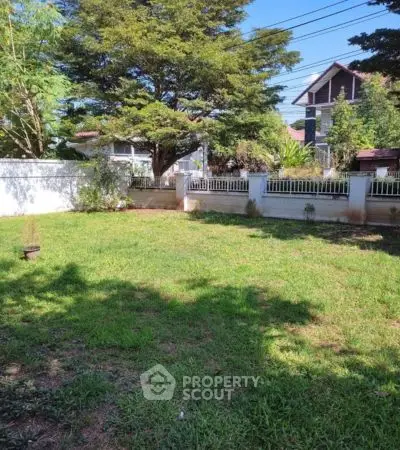 Spacious garden with lush greenery and charming fence in residential area
