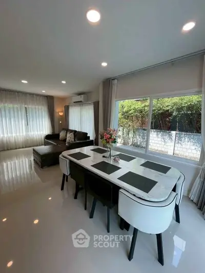 Spacious modern living room with elegant dining area and large windows offering garden views.