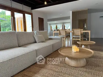 Spacious living room with modern furniture and natural light, featuring a cozy sofa and elegant dining area.