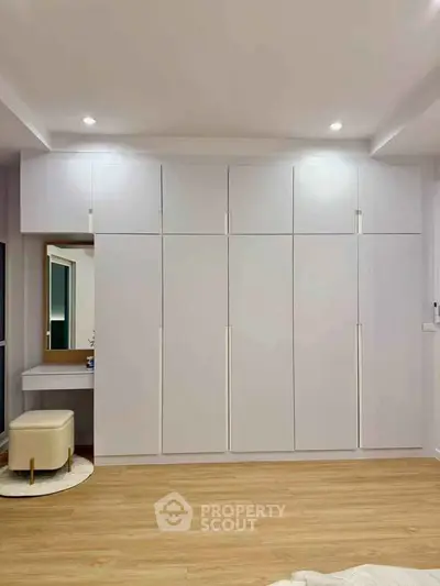 Spacious bedroom with modern built-in wardrobe and elegant vanity area.