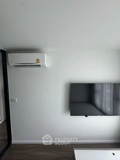 Modern living room with wall-mounted TV and air conditioning unit, sleek design.