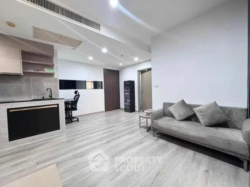 Modern living room with sleek kitchen and stylish decor in open layout apartment.