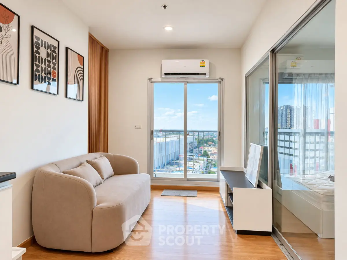 Modern living room with city view, featuring a cozy sofa and large windows for natural light.