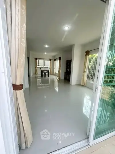 Spacious living room with elegant curtains and glossy white flooring