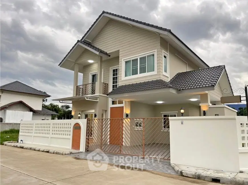 Modern two-story house with stylish exterior and gated entrance under cloudy sky.