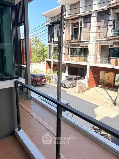 Modern townhouse balcony with street view and sleek railing design.