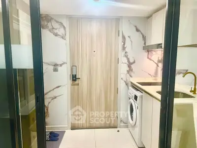 Modern apartment entrance with marble accents and in-unit washing machine