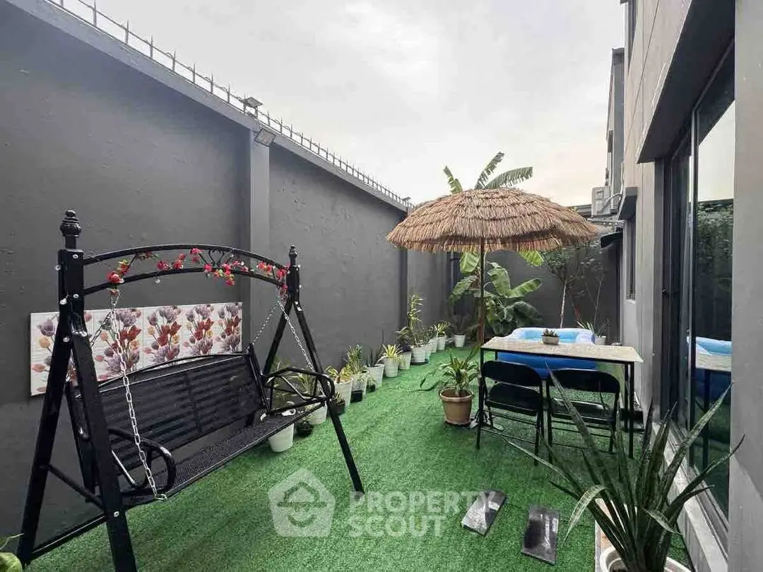 Charming garden patio with swing and tropical decor, perfect for relaxation.