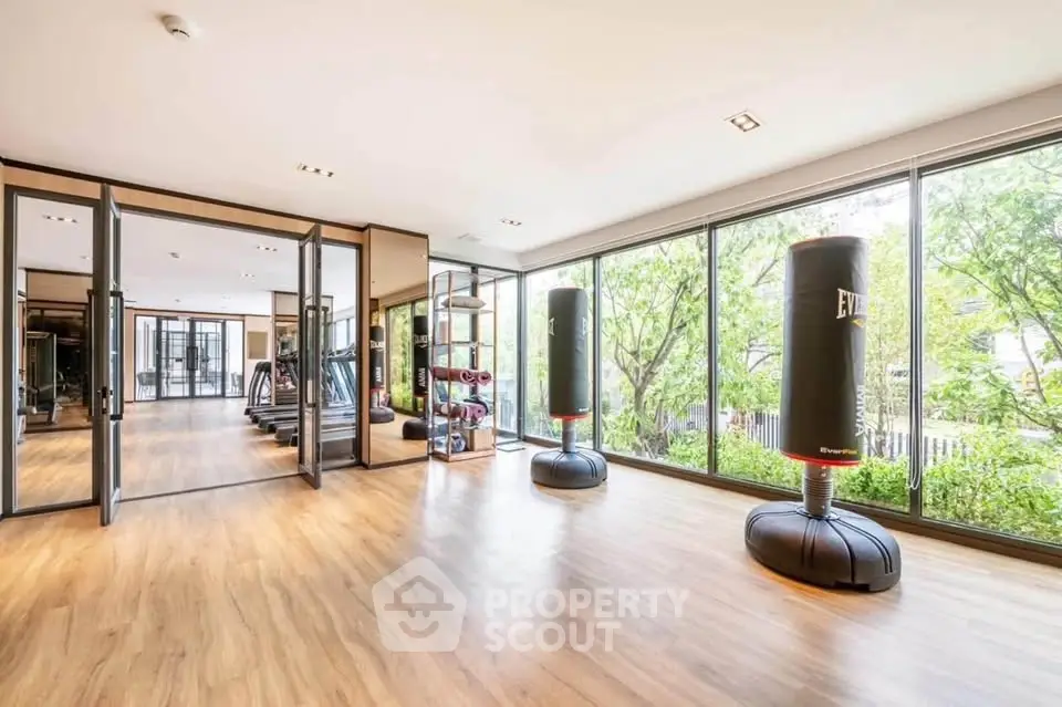 Spacious gym with floor-to-ceiling windows and modern equipment in luxury property.