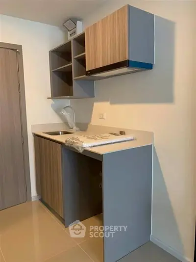 Modern compact kitchen with sleek cabinetry and integrated sink in a stylish apartment.
