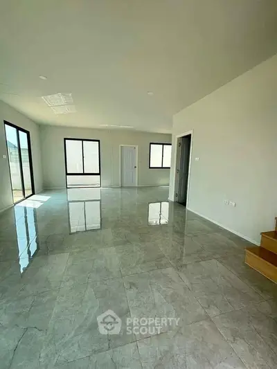 Spacious open-plan living area with glossy tiled floors and large windows for natural light.