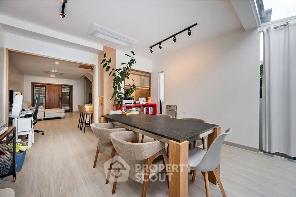 Spacious modern dining area with elegant wooden table and chairs, open layout leading to cozy living room.