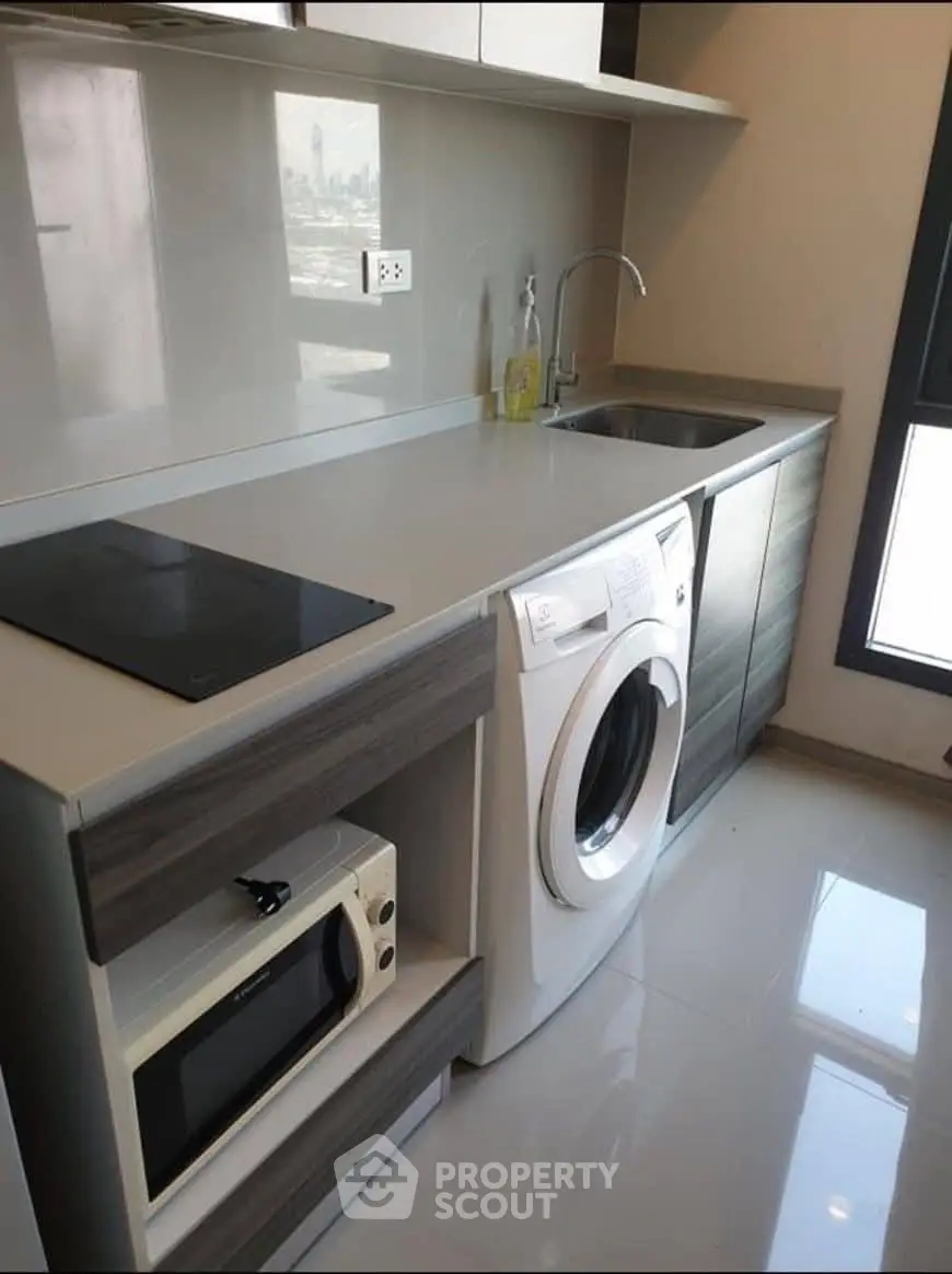 Modern kitchen with sleek appliances and washing machine in a compact layout.