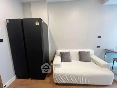Modern living room with sleek black fridge and cozy white sofa, perfect for urban living.