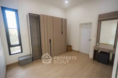Spacious bedroom with modern wardrobe and vanity in a bright, minimalist design.
