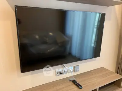 Modern living room with wall-mounted flat-screen TV and sleek wooden console.