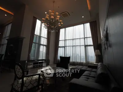 Luxurious high-ceiling living room with elegant chandelier and large windows offering stunning city views.