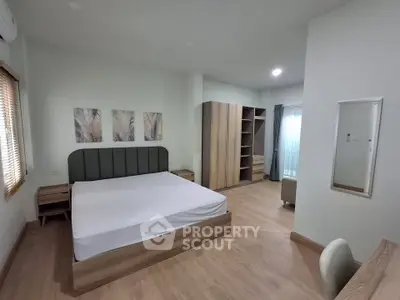 Spacious modern bedroom with wooden flooring and stylish furniture