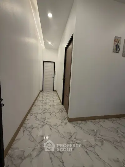Sleek modern hallway with marble flooring and recessed lighting in a contemporary home.