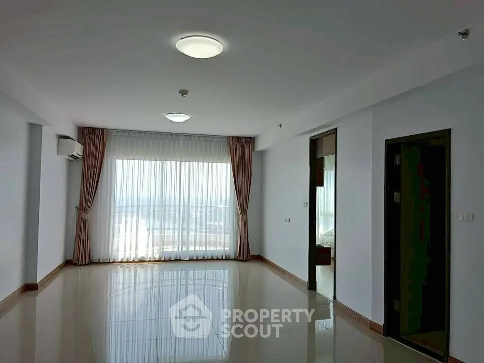 Spacious empty living room with large window and natural light