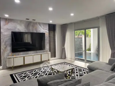 Luxurious living room with modern decor, large TV, and pool view, perfect for relaxation and entertainment.