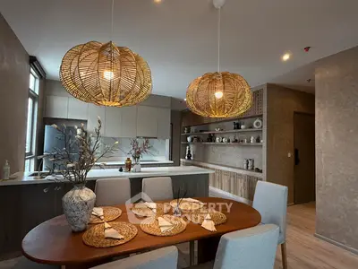 Stylish dining area with modern kitchen, featuring elegant lighting and natural decor.