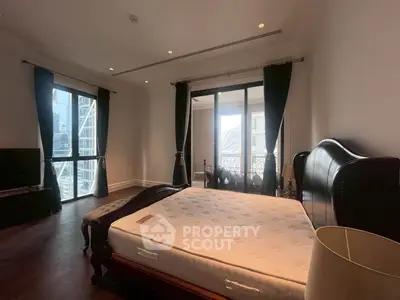 Luxurious bedroom with elegant furnishings and city view balcony.