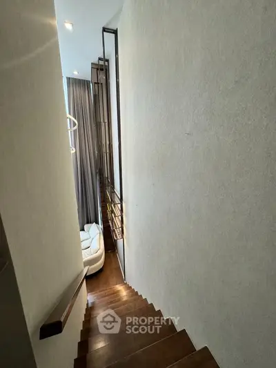 Elegant staircase leading to a modern living area with high ceilings and stylish decor.