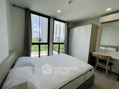 Modern bedroom with large windows and city view, featuring a comfortable bed and stylish furniture.