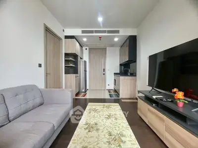 Modern living room with sleek kitchen, cozy sofa, and large TV, perfect for urban living.