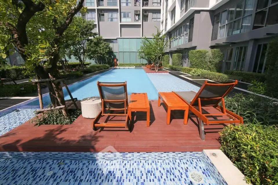 Luxurious apartment complex with inviting pool and sun loungers, perfect for relaxation and leisure.