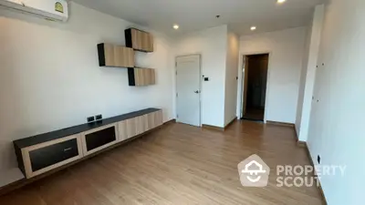 Modern unfurnished living room with wooden flooring and wall-mounted storage units