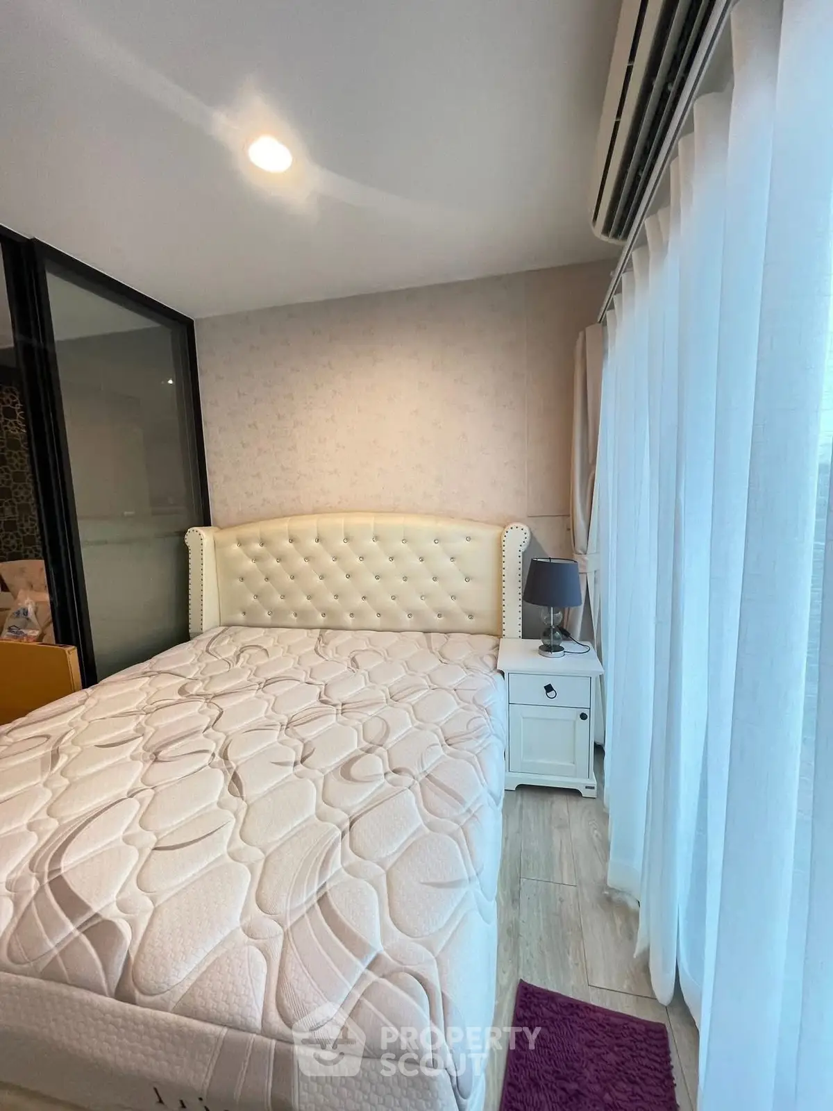 Modern bedroom with elegant white bed and natural light from large windows.