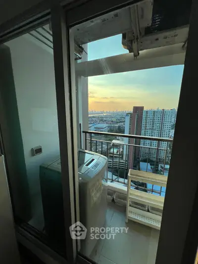 High-rise balcony with washing machine and stunning city skyline view at sunset.