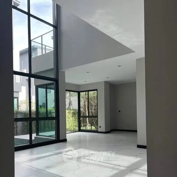 Spacious modern living room with high ceilings and large windows offering natural light.