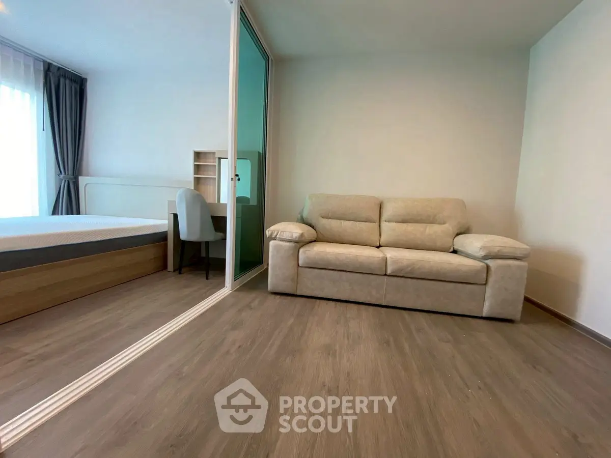 Modern studio apartment with cozy living area and bedroom separated by glass partition.