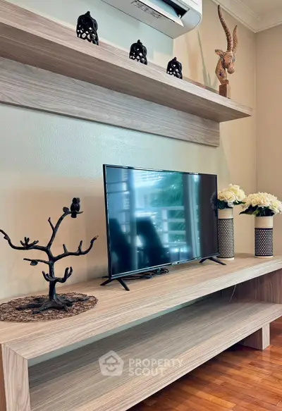 Stylish living room with modern TV setup and decorative accents on wooden shelves.